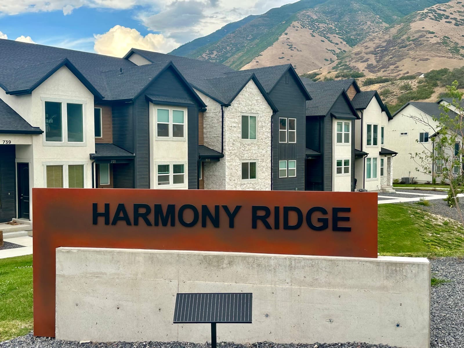 Harmony Ridge monument sign at the community entrance with townhomes and Maple Mountain behind