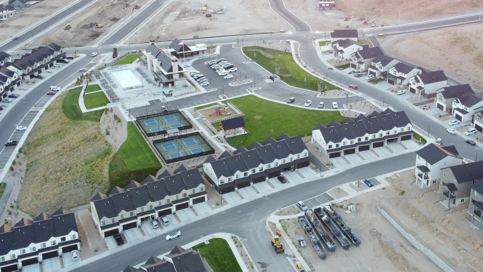 Close aerial view of the Inverness amenity core in Lehi — pool, clubhouse, pickleball courts, playground, and central green ringed by townhomes