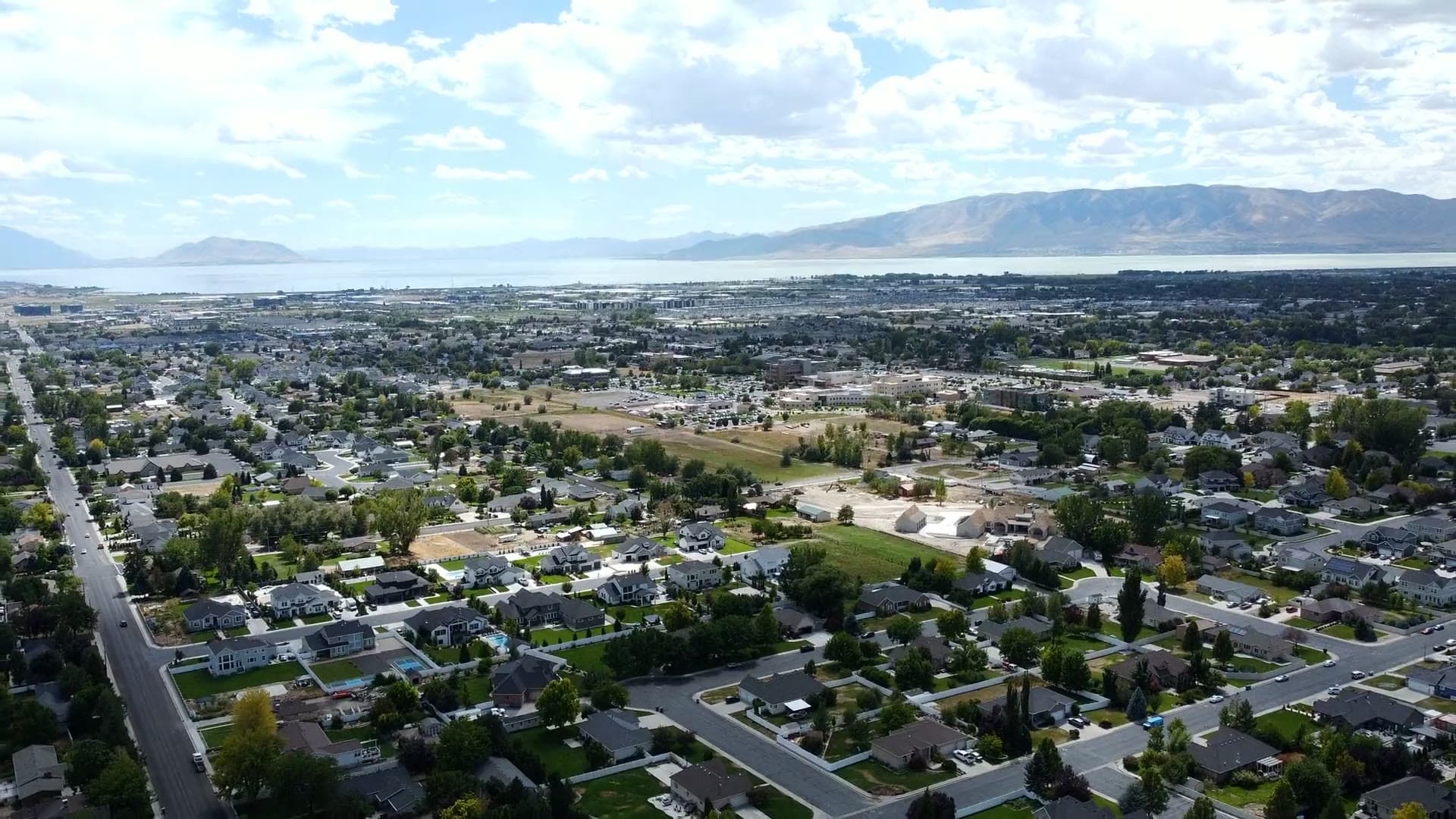 Aerial view over Utah Valley neighborhoods stretching toward Utah Lake, with new homes under construction