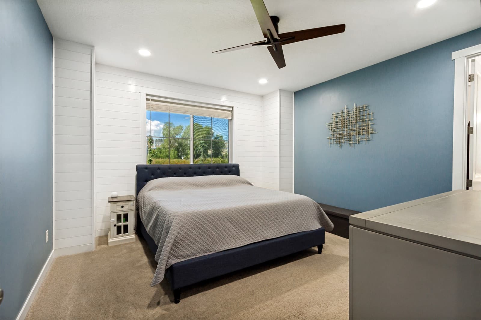 Primary bedroom with a white shiplap window wall, blue walls, and a ceiling fan
