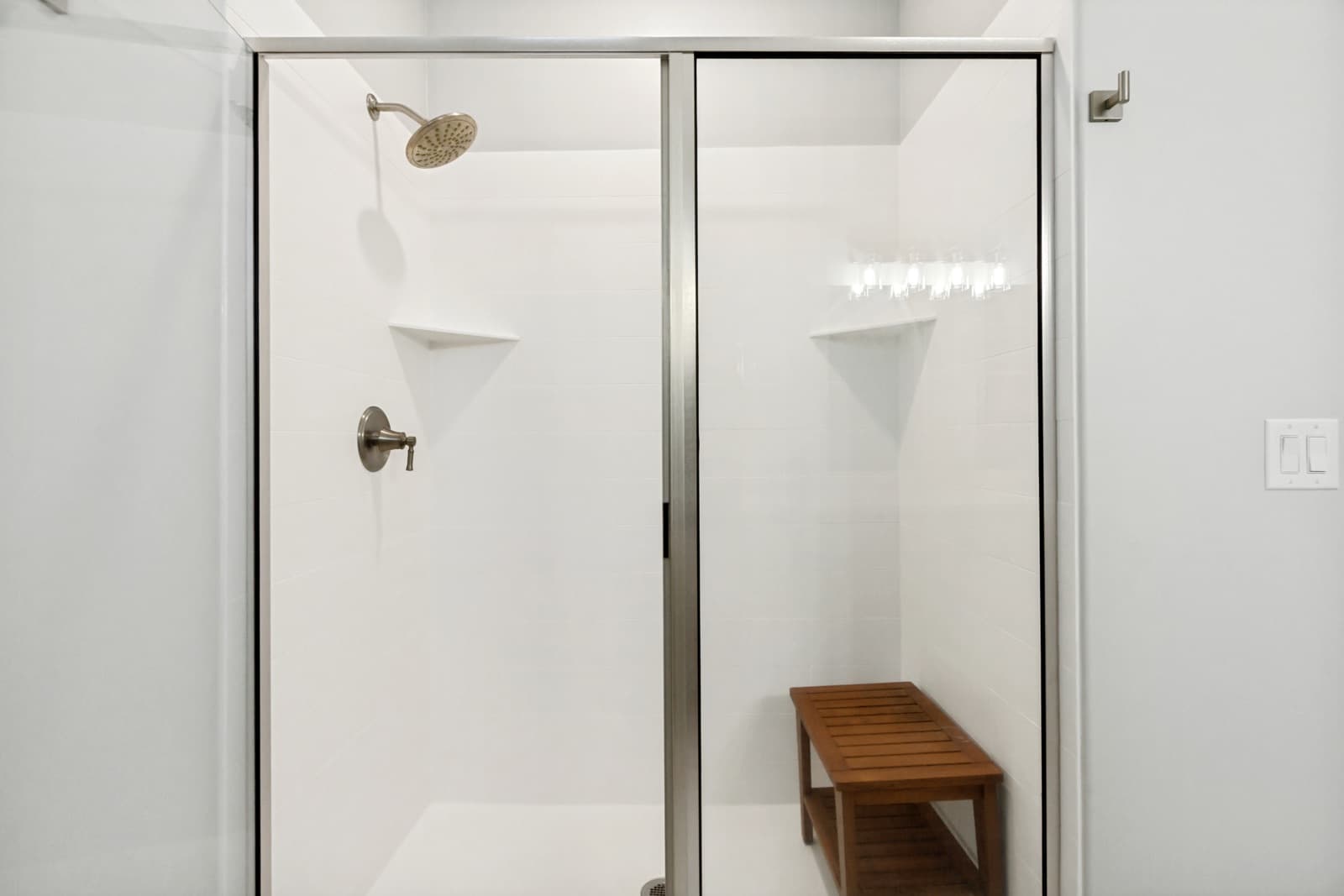 Walk-in shower with a glass door and a teak bench