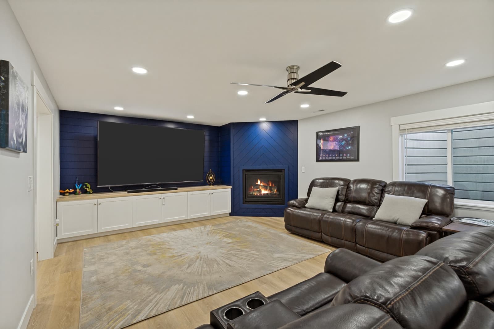 Basement family room with a navy shiplap wall, gas fireplace, and built-in media cabinetry