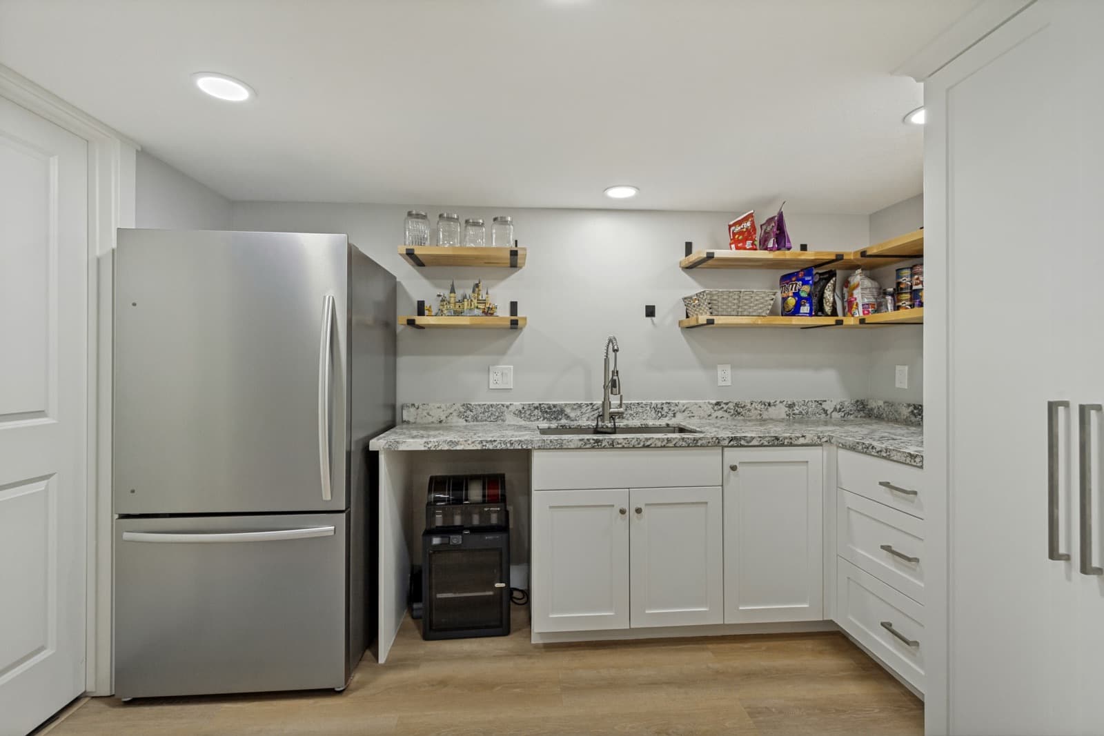 Basement kitchen with a refrigerator, granite counters, sink, and open shelves