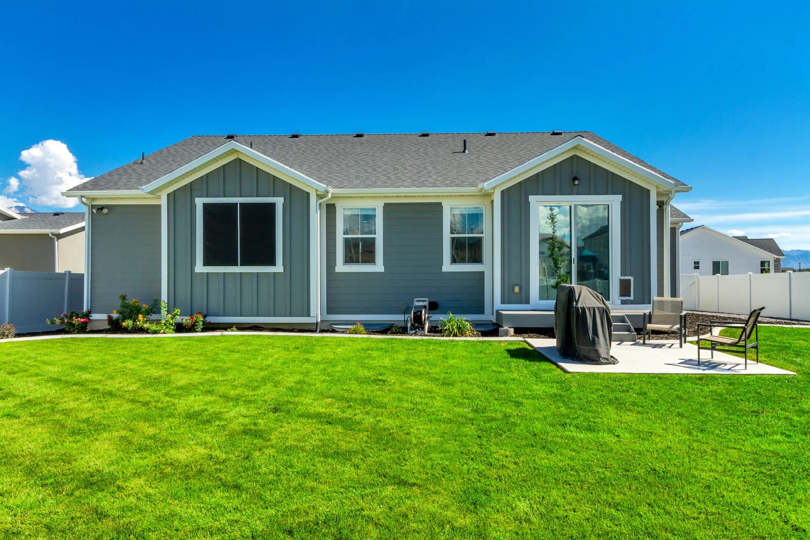 Back of the home with a patio and a large lawn