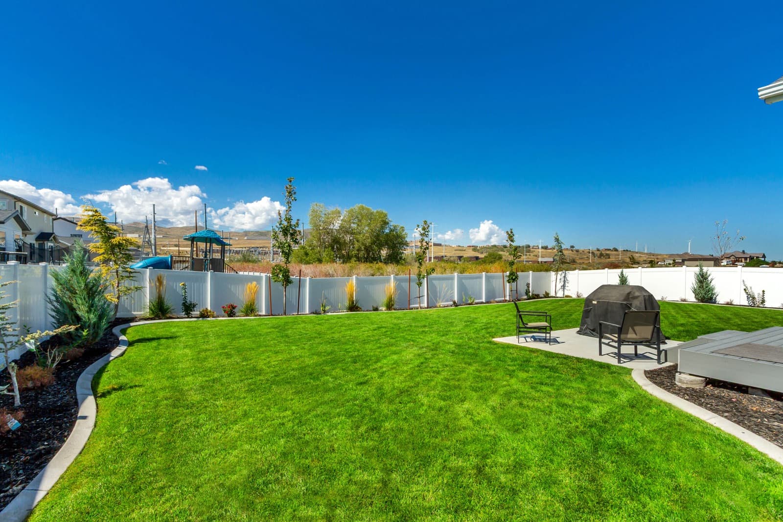 Curved lawn, patio, and white vinyl fence