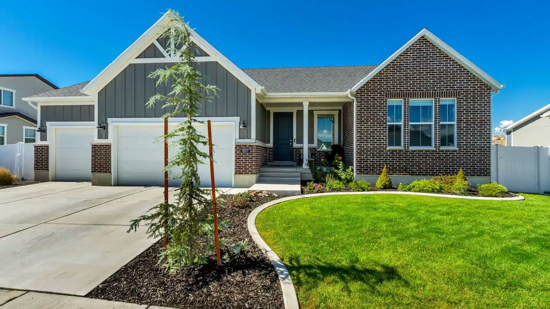 3007 N Twin Flower Way in Lehi — a brick and gray board-and-batten rambler with a three-car garage and a curved front lawn