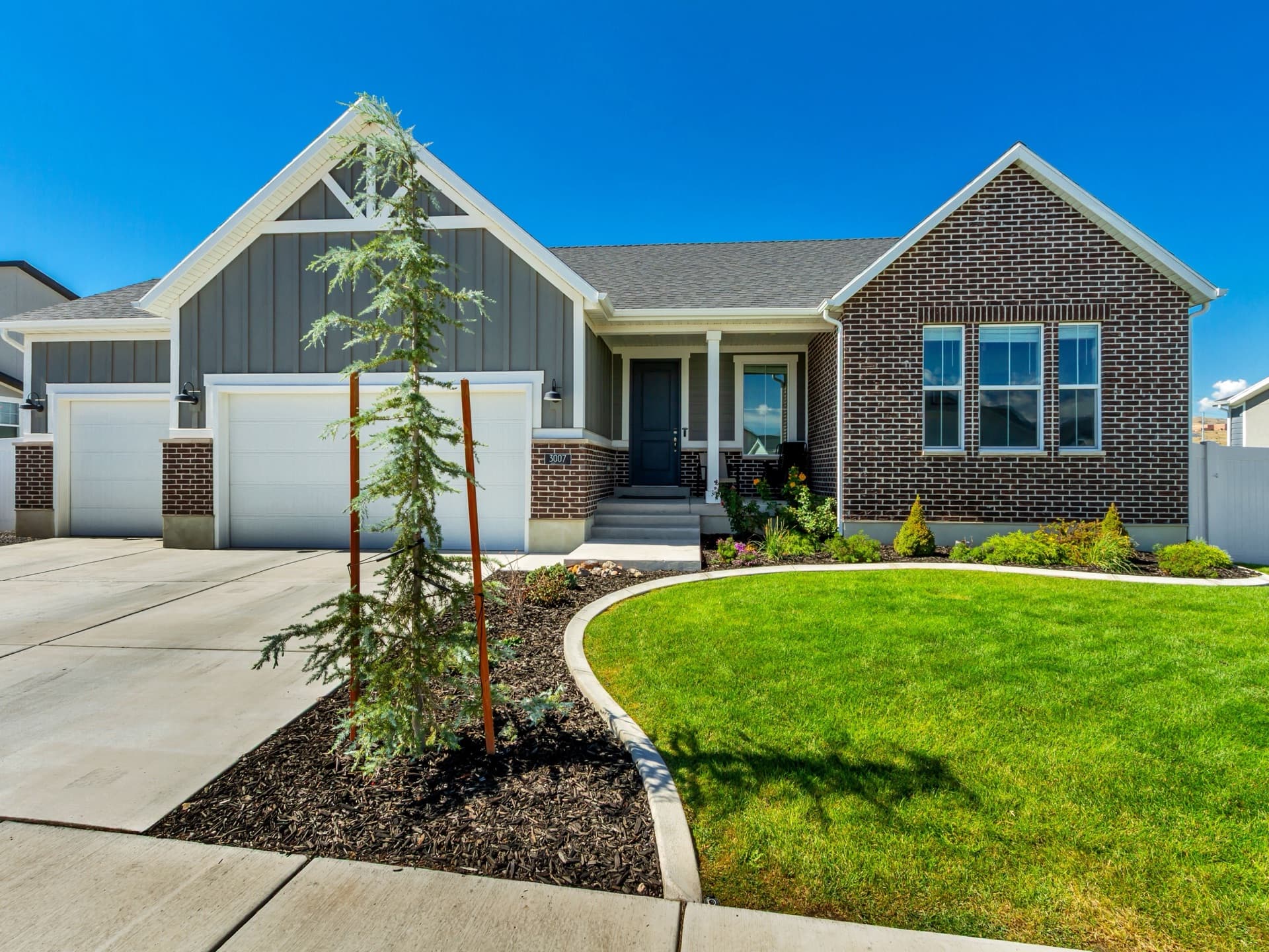 3007 N Twin Flower Way in Lehi — a brick and gray board-and-batten rambler with a three-car garage and a curved front lawn