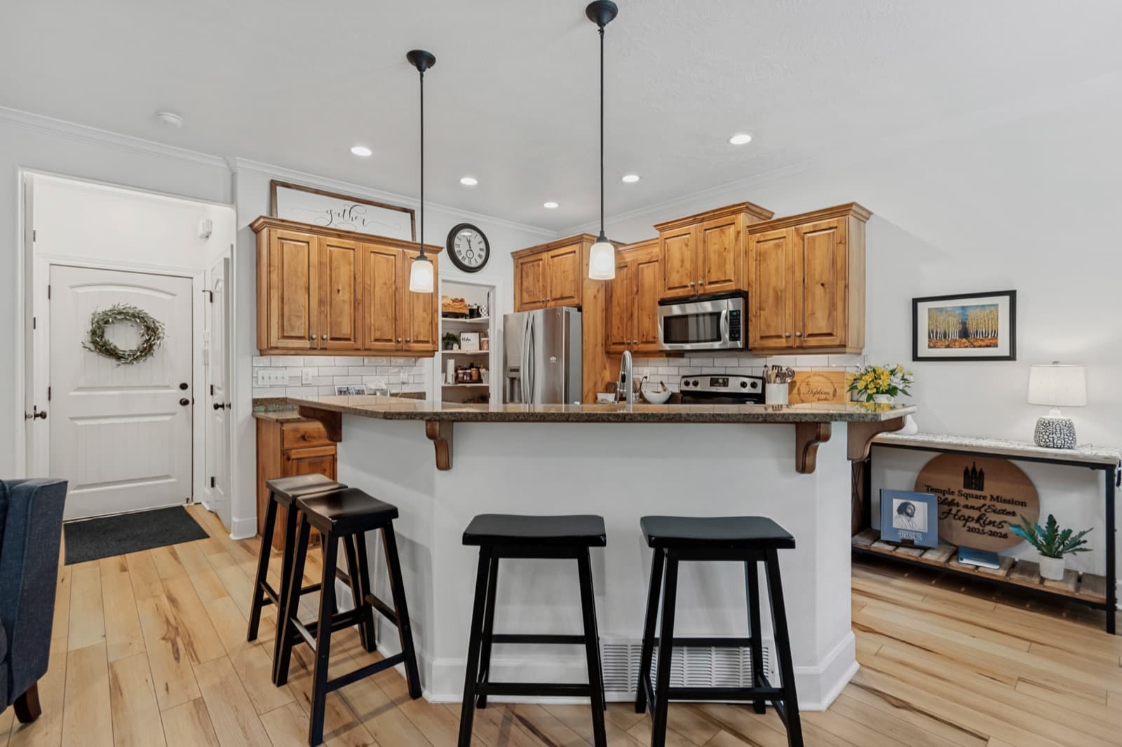 Kitchen with knotty alder cabinetry, granite counters, an island with three bar stools, and stainless appliances