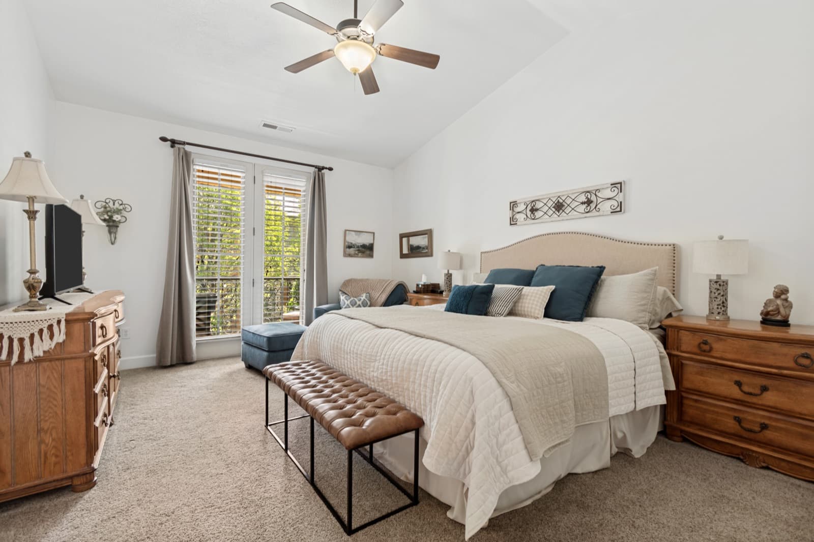 Vaulted primary bedroom with a ceiling fan and French doors opening to the balcony