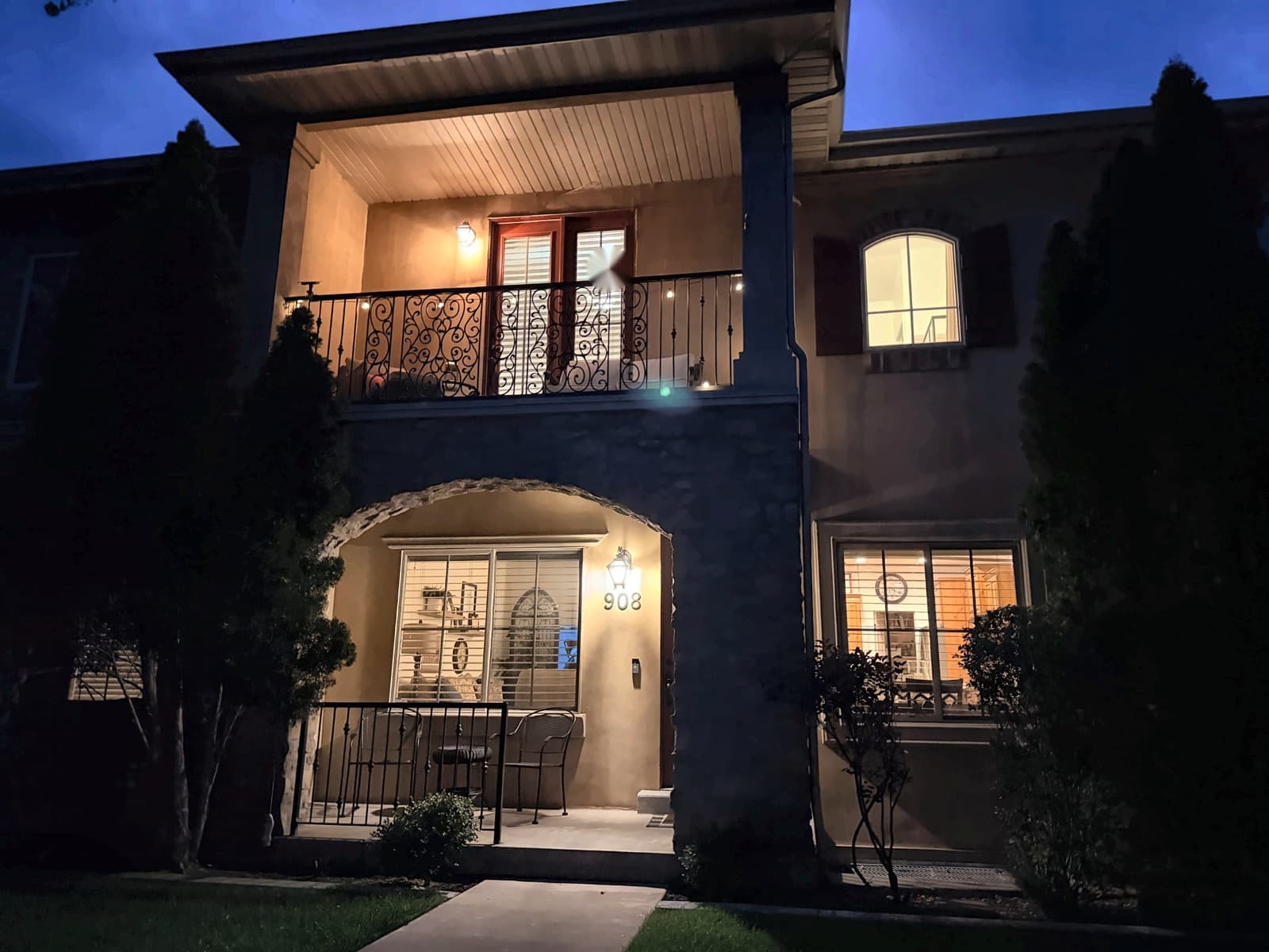 Front of the townhome at blue hour with the porch and balcony lit